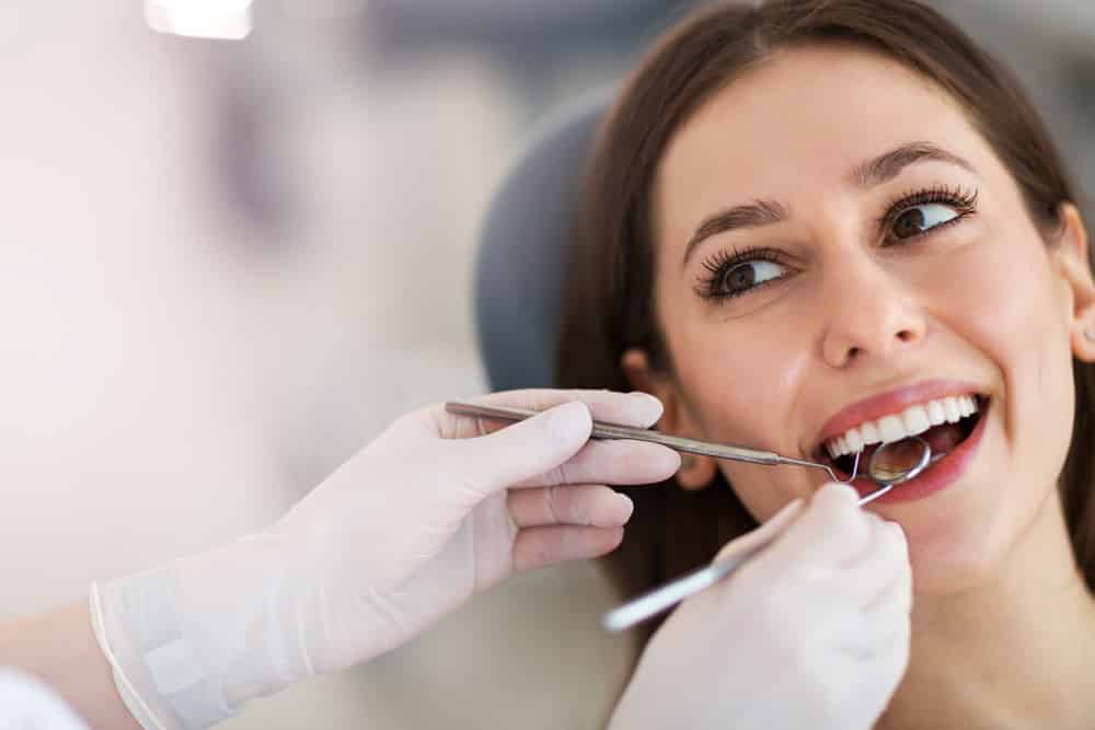 Dentist Examining Teeth Of Young Woman